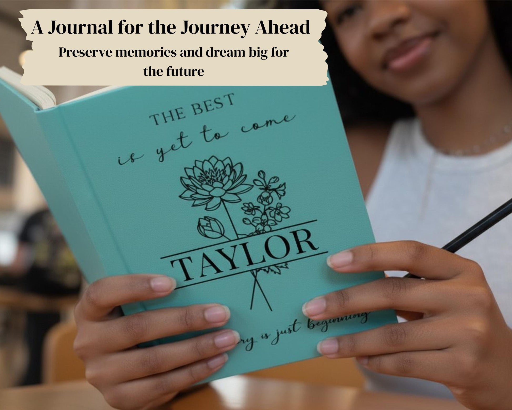 A person is holding a turquoise journal with the title "The Best is yet to Come" and the name "Taylor" printed on it.