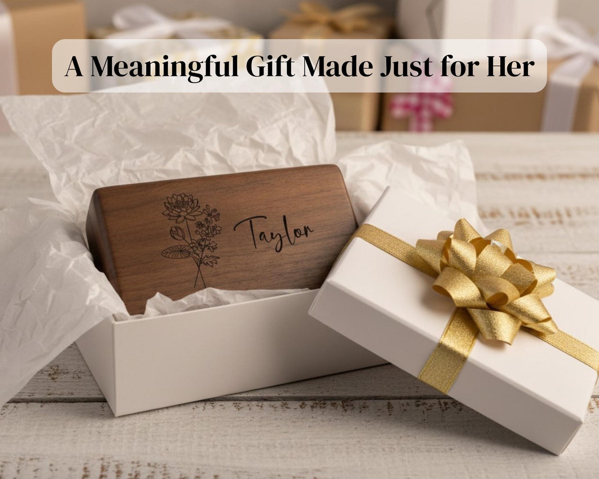A wooden box with a personalized name engraved on it, placed on a white surface with a gold bow.