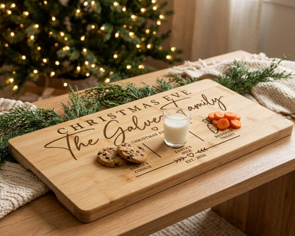 A wooden cutting board with a personalized message and a glass of milk, surrounded by holiday decorations and greenery.