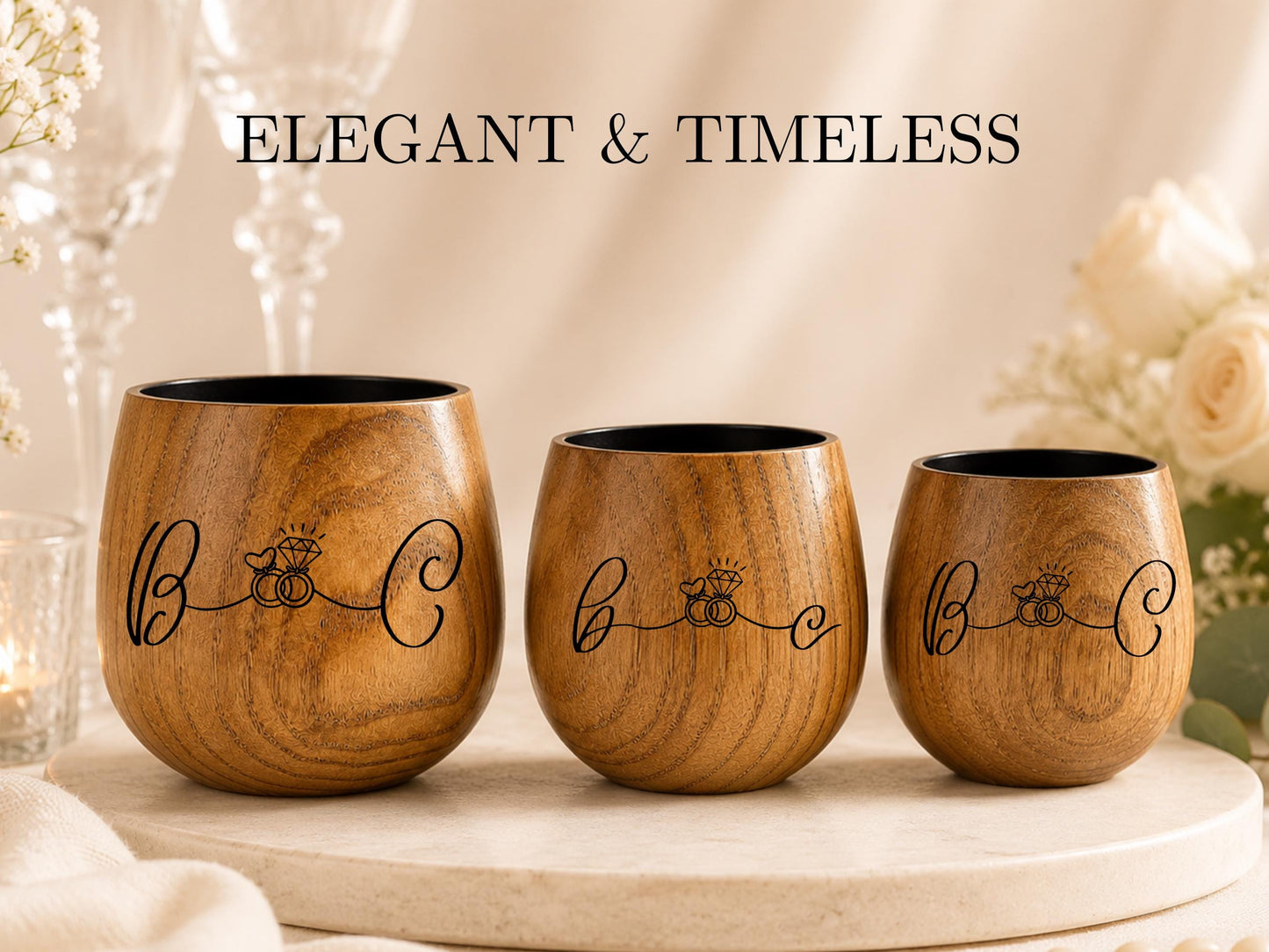 Three wooden wine glasses with the text "Elegant & Timeless" printed on them, placed on a table with white flowers in the background.