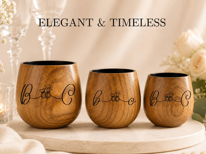 Three wooden wine glasses with the text "Elegant & Timeless" printed on them, placed on a table with white flowers in the background.