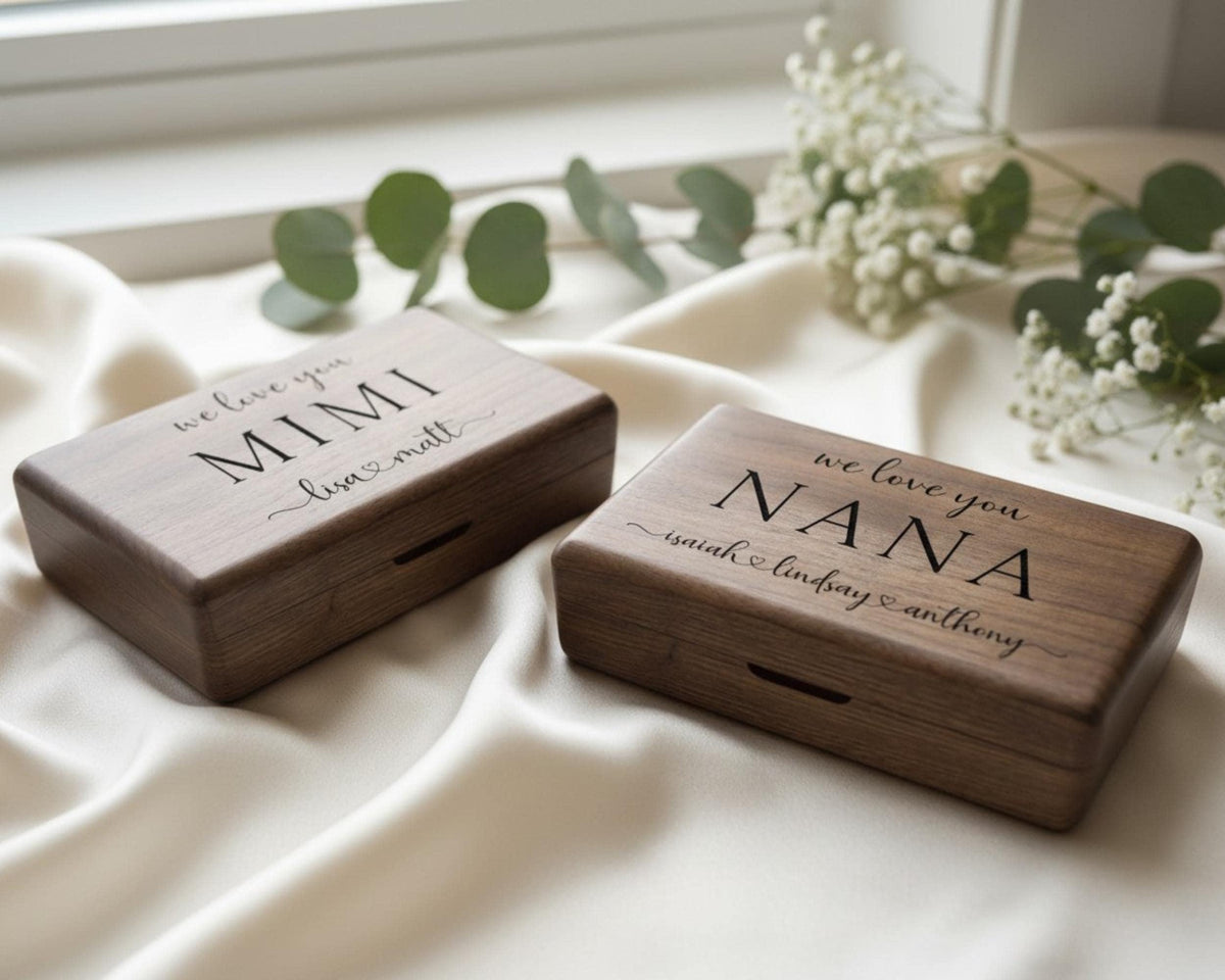 Two wooden boxes with personalized messages on them, placed on a white cloth near some greenery.