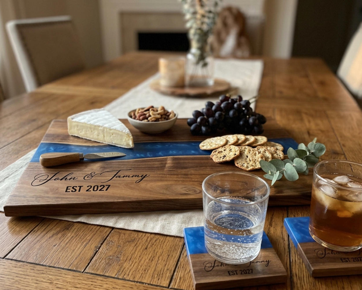 a wooden cutting board with a variety of food items, including cheese, grapes, crackers, and a knife, placed on a dining table. There are also two glasses of water and two glasses of tea or other beverages.