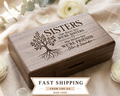 A wooden box with a tree design and text engraved on it, placed on a beige cloth with white flowers.