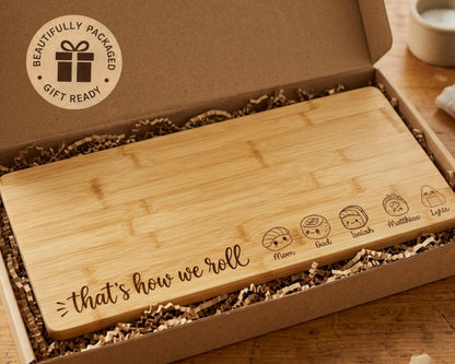 A wooden cutting board with a humorous message engraved on it, placed in a cardboard box with shredded paper.