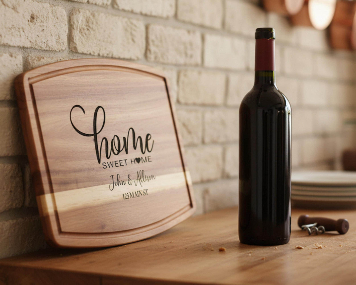 A wooden cutting board with the text "Home Sweet Home" and "John & Allison" engraved on it, along with a bottle of red wine, is placed on a wooden table.