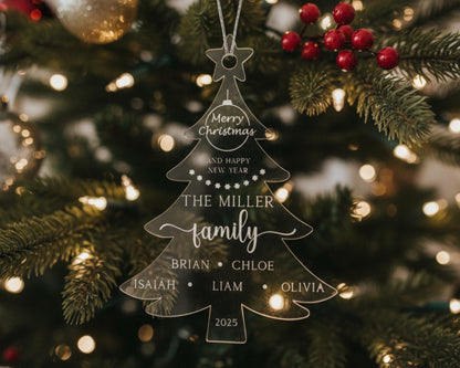 A clear Christmas ornament shaped like a tree hangs on a decorated tree, surrounded by twinkling lights and red berries.