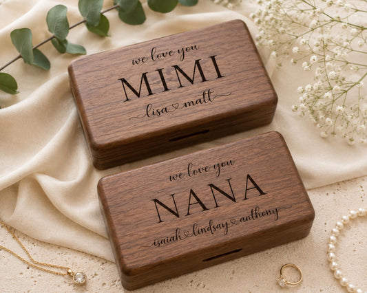 Two wooden boxes with personalized messages, placed on a beige cloth and surrounded by pearls and greenery.