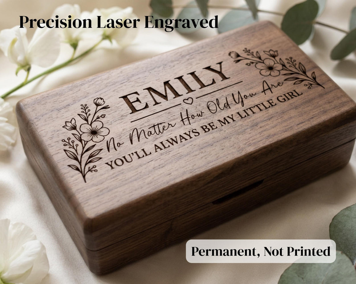 A wooden box with a personalized engraved message on it, surrounded by white flowers.