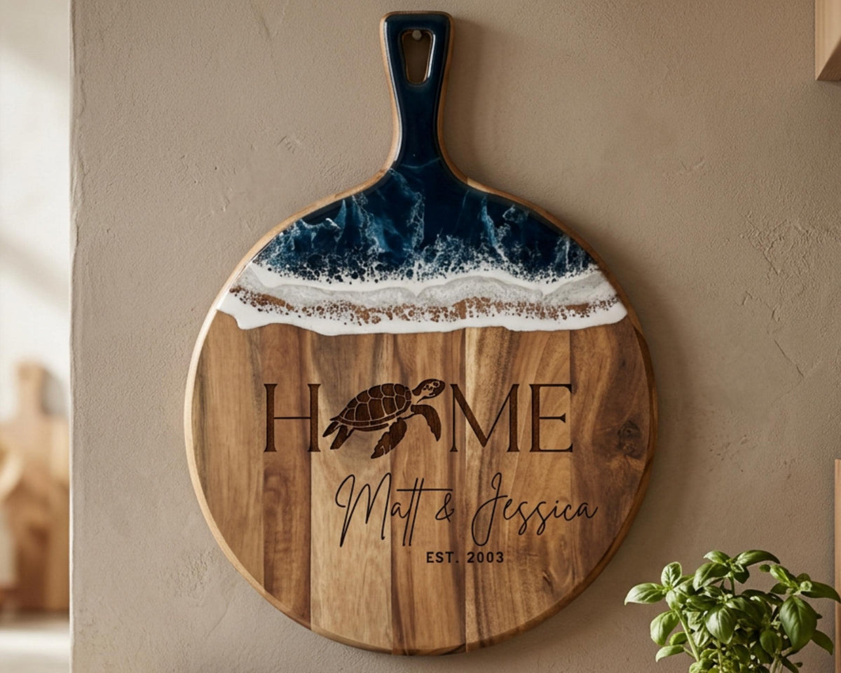 A wooden cutting board with a blue and white design, featuring the text "HOME Matt & Jessica EST. 2003" and a turtle image.