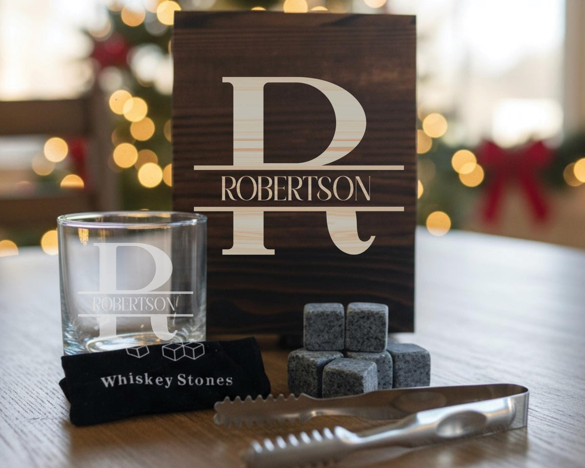 a wooden sign with the name "ROBERTSON" on it, along with a glass and whiskey stones, all placed on a wooden table.