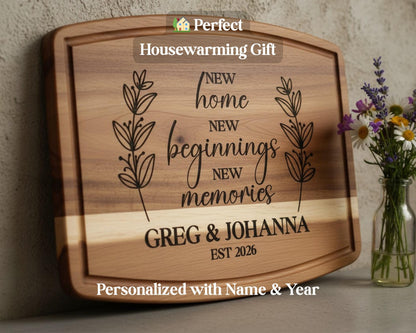 A wooden cutting board with a personalized message engraved on it, along with a vase of flowers and a housewarming gift sign.