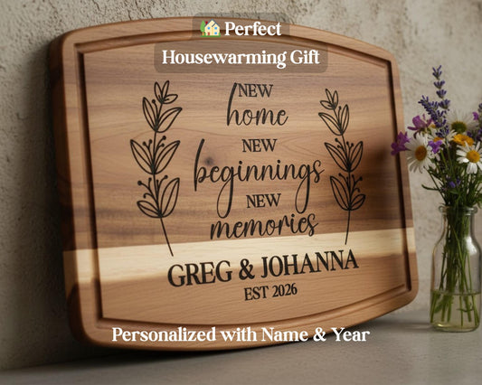 A wooden cutting board with a personalized message engraved on it, along with a vase of flowers and a housewarming gift sign.
