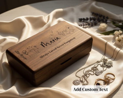 A wooden box with a personalized message engraved on it, surrounded by jewelry and flowers on a white cloth.