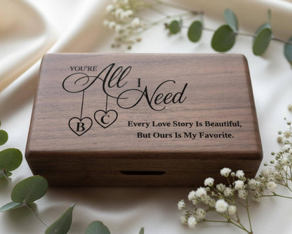 A wooden box with a personalized message engraved on it, surrounded by white flowers and greenery.