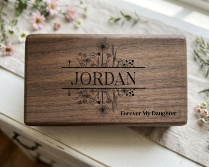 A wooden box with the name "JORDAN" engraved on it, surrounded by floral designs.