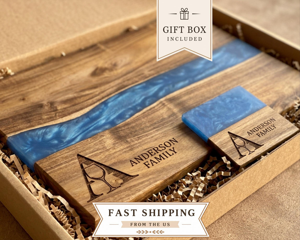 Wine charcuterie board with a blue resin river in a gift box beside a small engraved family plaque