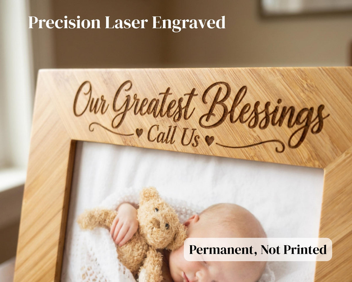 A wooden picture frame with a photo of a sleeping baby inside, along with the text "Our Greatest Blessings Call Us" engraved on the frame.