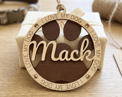 A wooden ornament with the word "Mack" engraved on it, surrounded by paw prints and the phrase "I LOVE MY DOG".