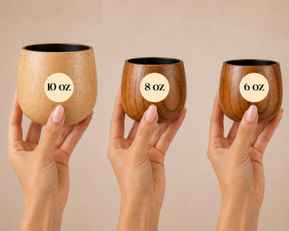 Three wooden cups are being held up against a light background, each labeled with its volume in ounces.