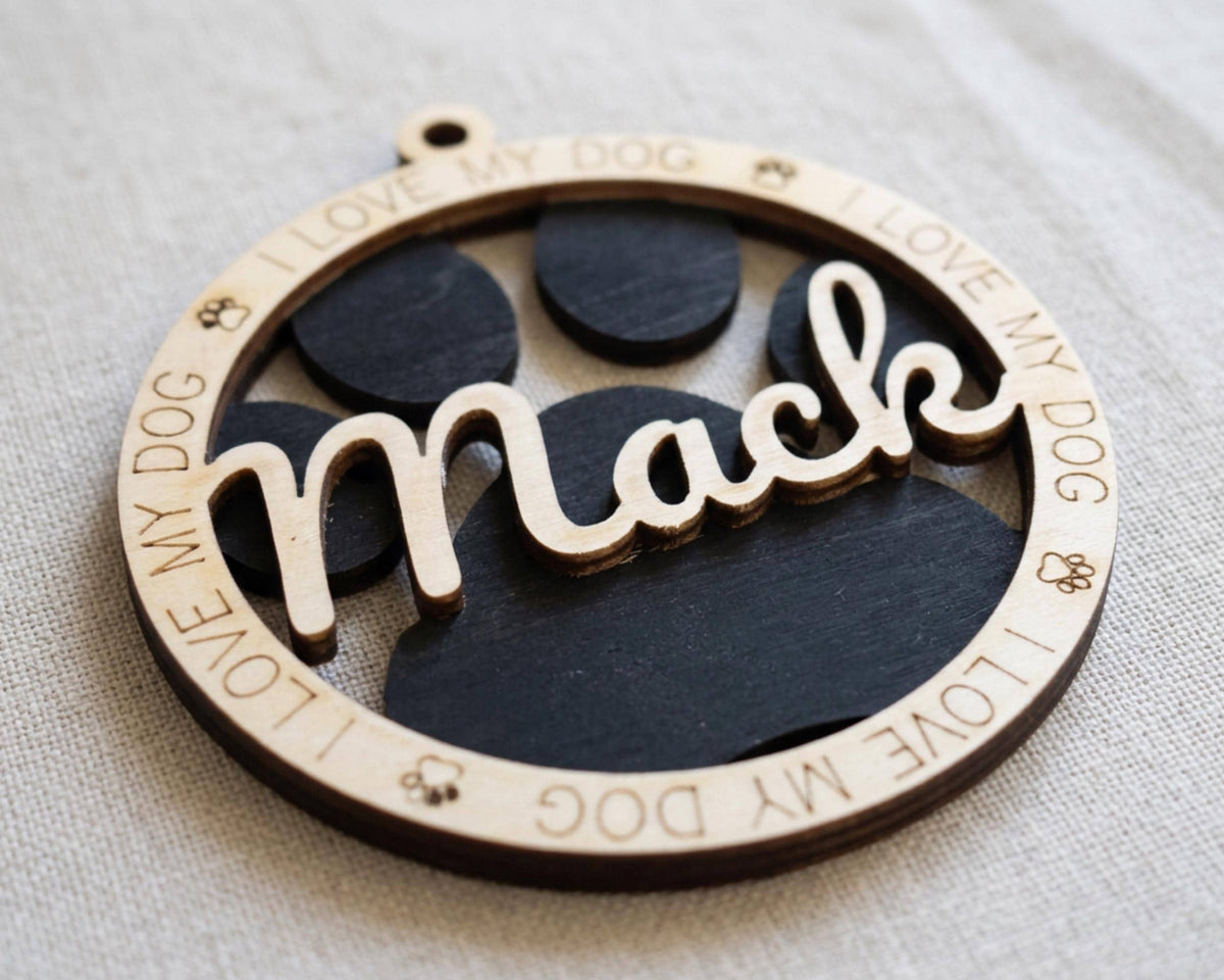 A wooden ornament with the word "Mack" engraved on it, surrounded by paw prints.