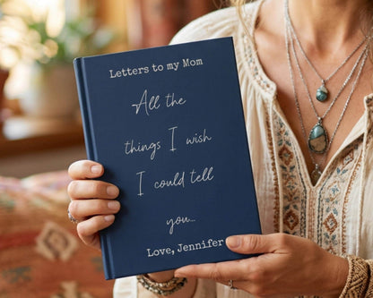 A person is holding a blue book titled "Letters to my Mom All the things I wish I could tell you..." by Jennifer, with the subtitle "Love, Jennifer".