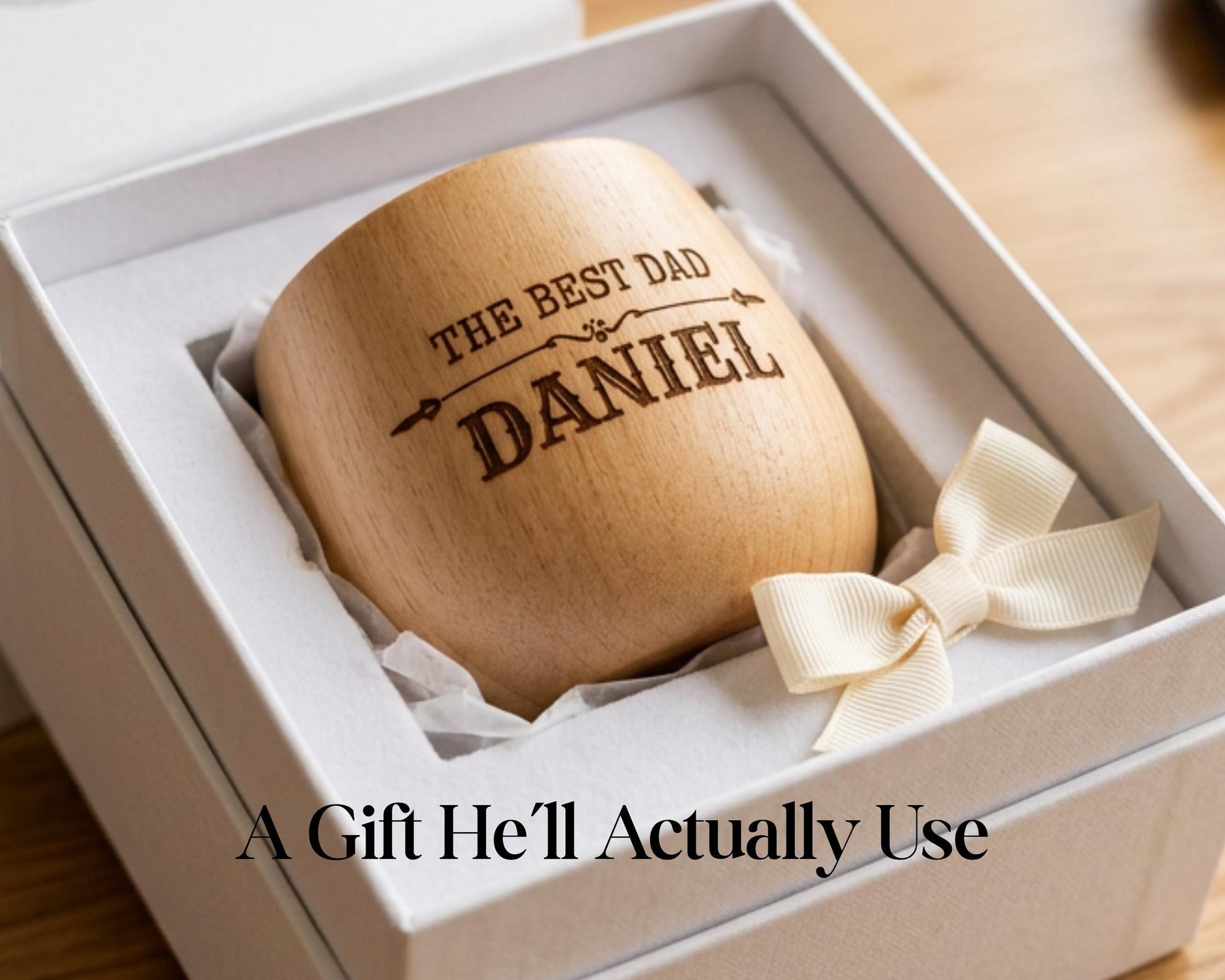 A wooden mug with the text "THE BEST DAD DANIEL" engraved on it, placed in a white box with a ribbon bow.