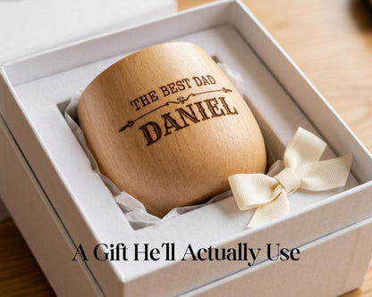 A wooden mug with the text "THE BEST DAD DANIEL" engraved on it, placed in a white box with a ribbon bow.
