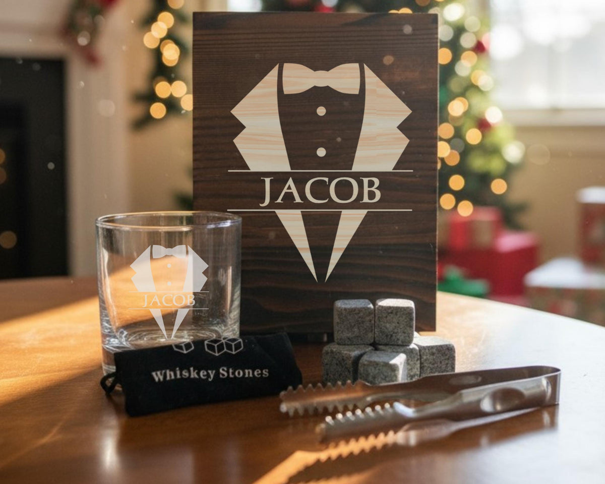 a set of whiskey-related items, including a glass, whiskey stones, and a wooden box with a tuxedo design.