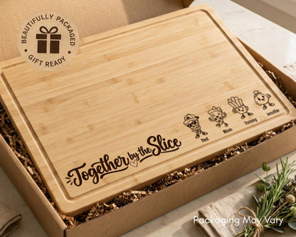 A wooden cutting board with a decorative design and text, placed in a cardboard box with some shredded paper.