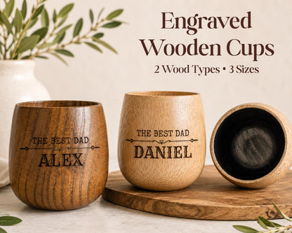 three engraved wooden cups, each with a personalized message engraved on them. The cups are made of wood and have a natural, rustic appearance. The cups are placed on a wooden surface, and there is a vase of greenery in the background. The image also includes text that reads "Engraved Wooden Cups 2 Wood Types * 3 Sizes" and "THE BEST DAD ALEX DANIEL".