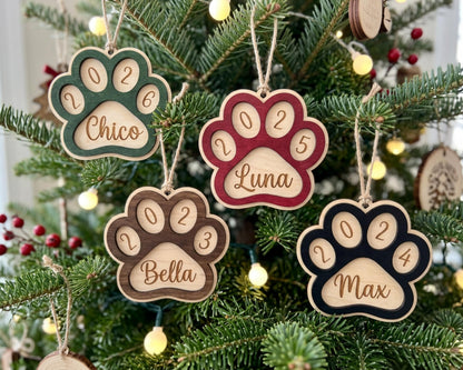 A Christmas tree decorated with personalized wooden paw print ornaments, each with a unique name and year.
