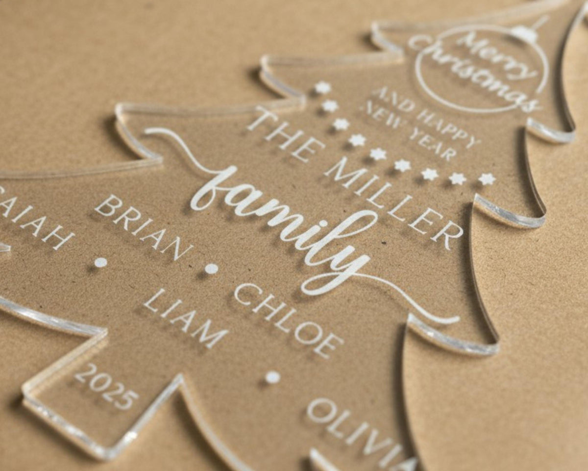 Close-up of a clear acrylic Christmas tree ornament engraved with a family name and personalized names